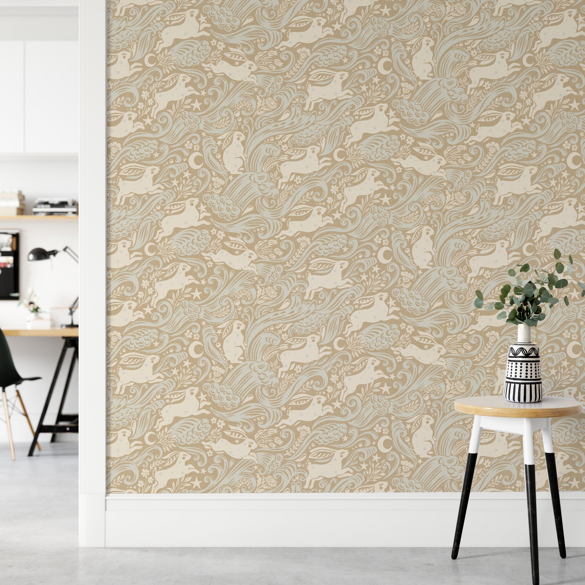 Celestial Sea Rabbit gold wallpaper of rabbits, birds and moons behind a white stool and patterned vase near a desk