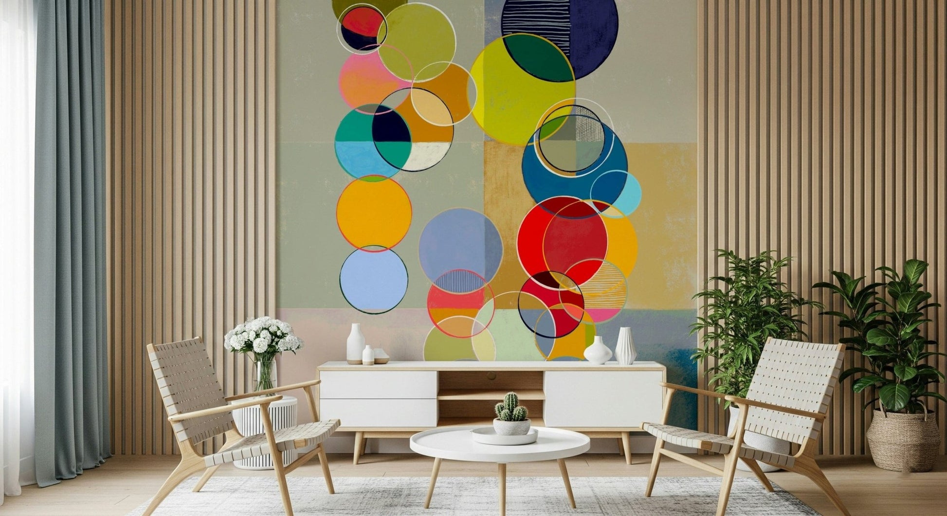Chromatic Circles wallpaper mural of bright circles behind a white sideboard and woven lounge chairs