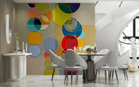 Chromatic Circles wallpaper mural of colorful circles behind a dark round dining table and gray chairs
