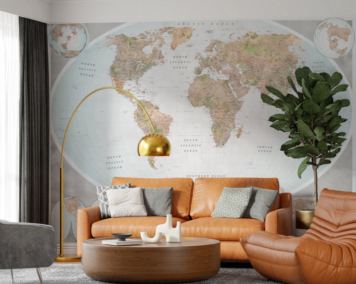 Classic world map in blue and earthy tones wallpaper mural behind a tan leather sofa and gold arc lamp in a living room