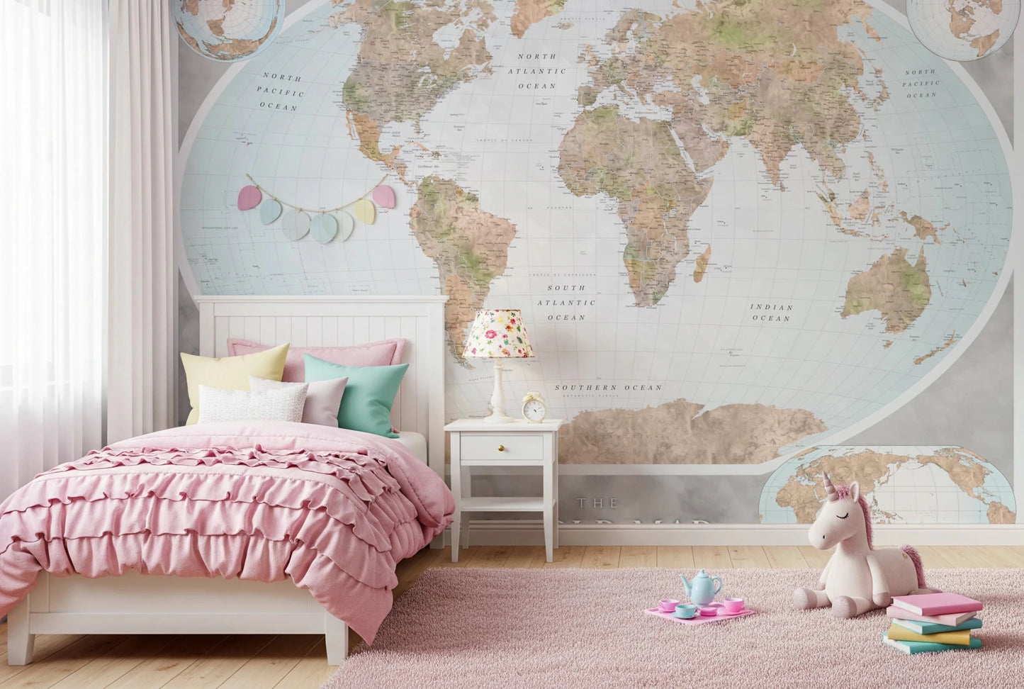 Classic world map in blue and earthy tones wallpaper mural behind a pink ruffled bed and unicorn plush in a girls room