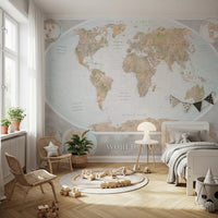 Classic world map in blue and earthy tones wallpaper mural above a white bed and rattan chairs in a soft kids room