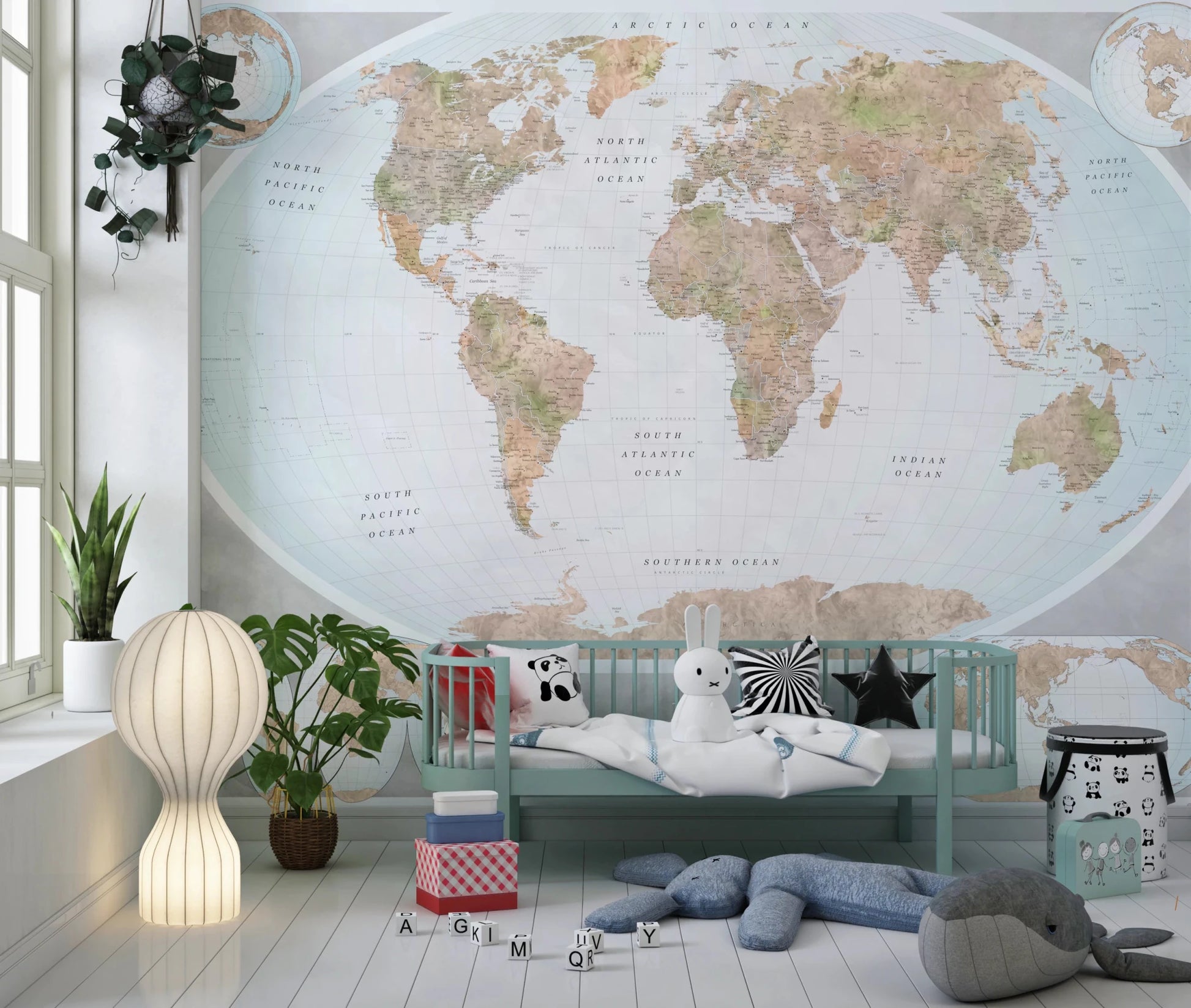 Classic world map in blue and earthy tones wallpaper mural behind a mint daybed with plush toys in a kids room