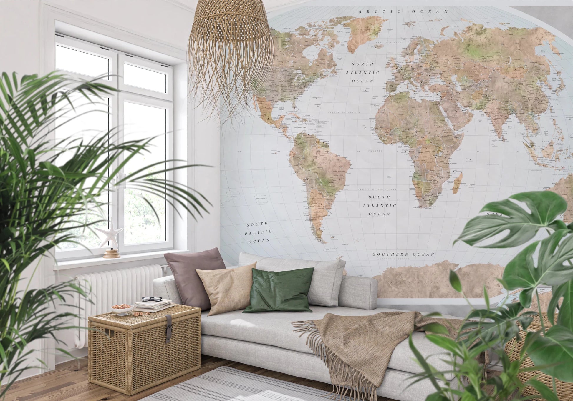 Classic world map in blue and earthy tones wallpaper mural behind a gray sofa and rattan pendant amid leafy plants