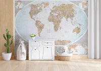 Classic world map in blue and earthy tones wallpaper mural above a white dresser with a teddy basket in a nursery