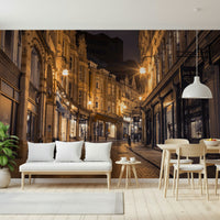Cobblestone Street Nights wallpaper mural in a dining area with a white bench and light wood table