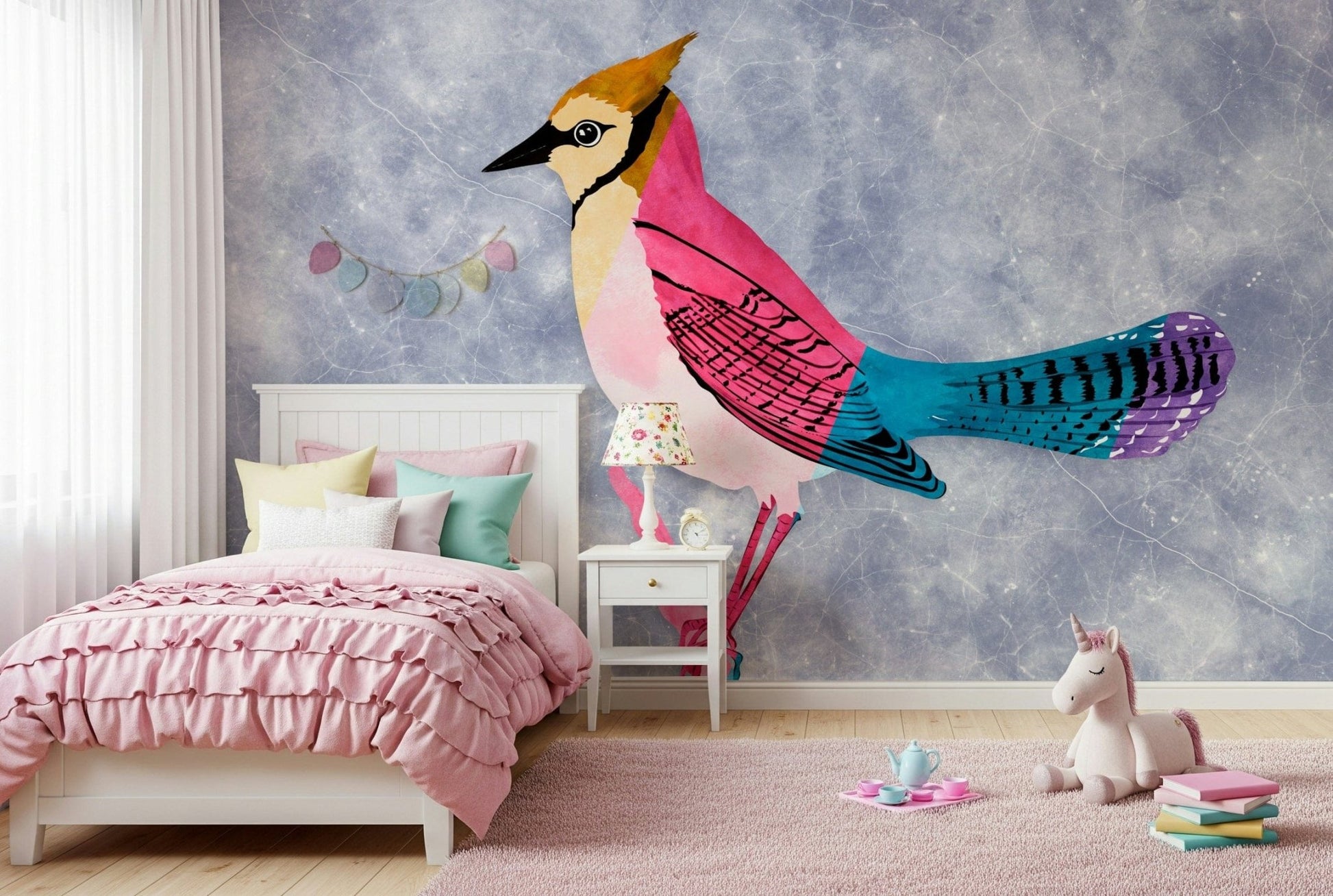 Colorful Jay wall mural in pink and blue behind a white ruffled bed and unicorn plush in a girls bedroom