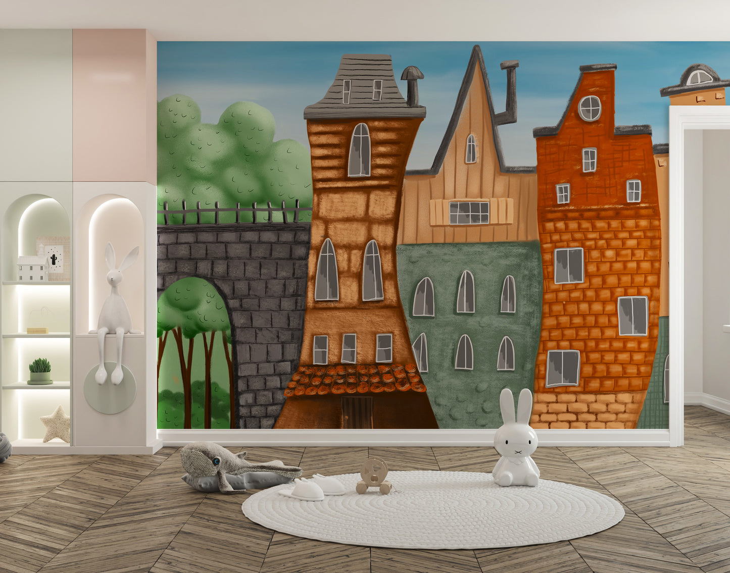 Small Painted City wallpaper mural of orange and green houses in a nursery with a round rug and bunny toys