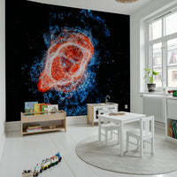 Cosmic Bloom wall mural of a red and blue galaxy behind a white kids table and toy train in a bright playroom
