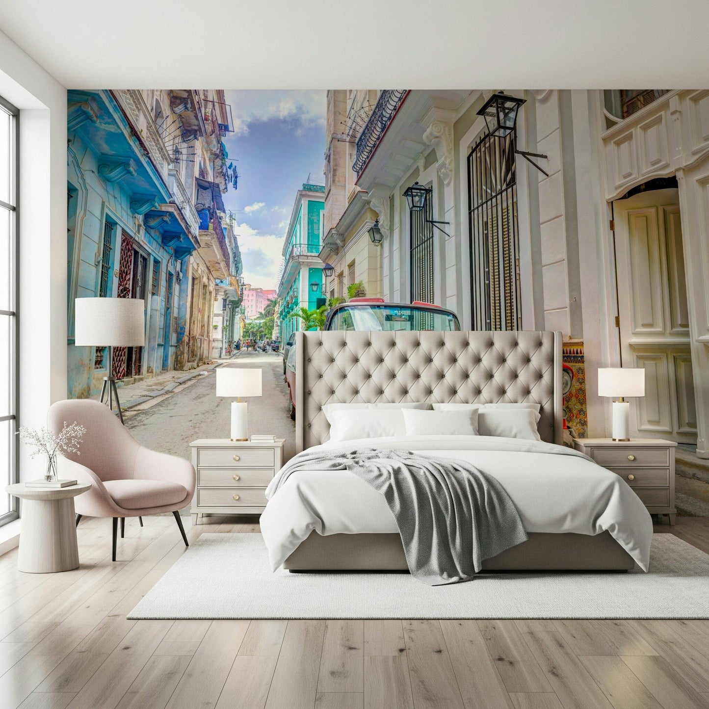 Cuban Classics wallpaper mural of a Havana street behind a tufted bed and pink chair in a bedroom