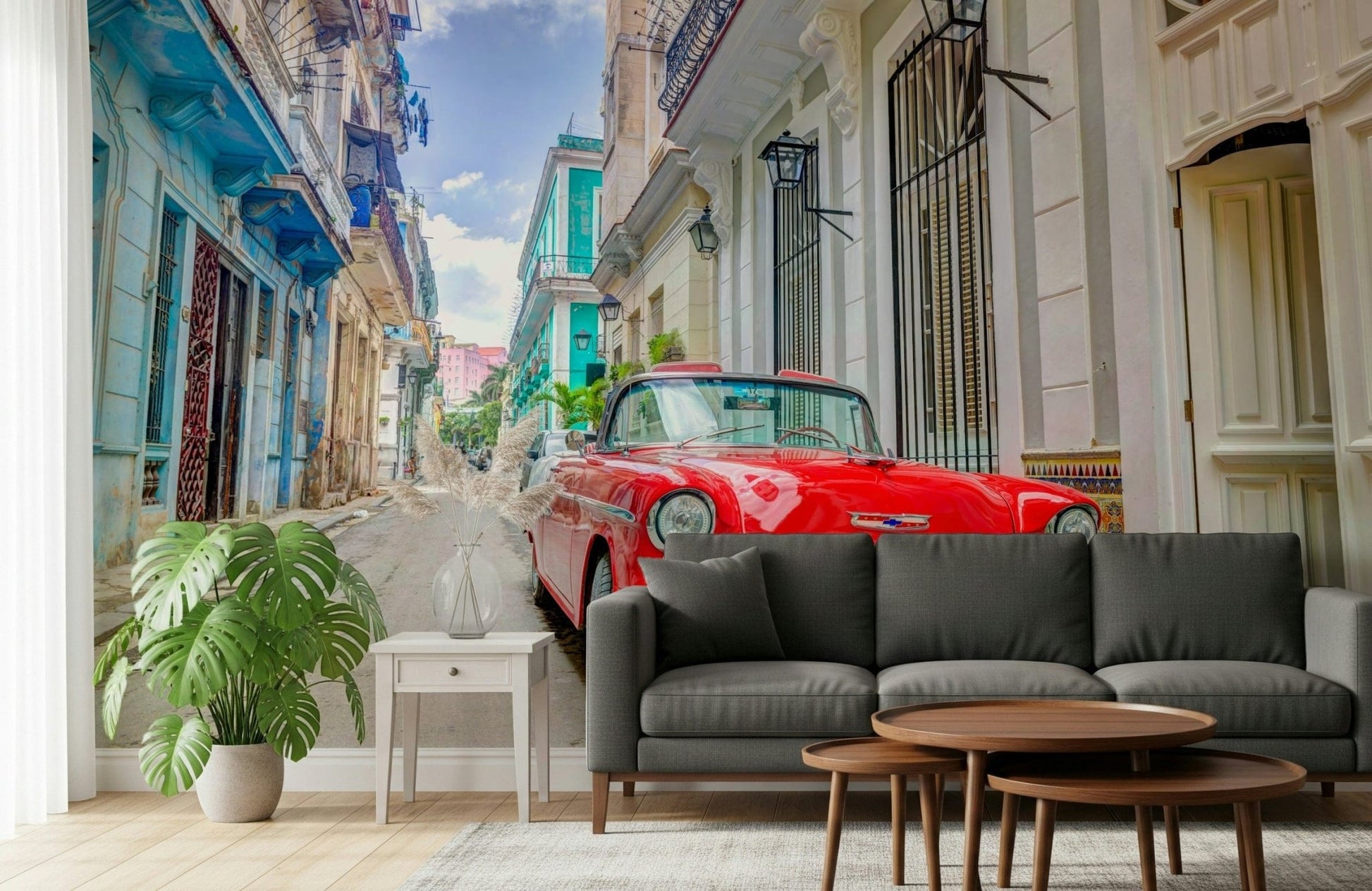 Cuban Classics wallpaper mural of a red vintage car behind a dark grey sofa and monstera in a living room