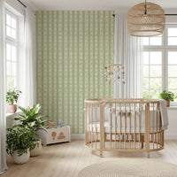 Daisy Chain Delight wallpaper mural in a nursery behind a wood crib with a pompom mobile and leafy plants