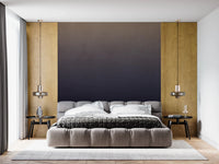 Dirty Paper - Ombre Dusk wallpaper mural of a gold-to-navy gradient behind a grey tufted bed with gold panels