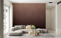 Dirty Paper Ombre Peach wall mural fading to brown behind a grey sectional with yellow cushion in a bright living room