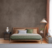 Dirty Paper Taupe wall mural in warm brown behind a wood bed with green bedding and a pleated arc floor lamp