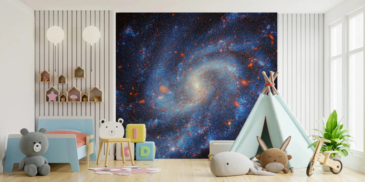 Distant Starfield wallpaper mural of a blue spiral galaxy behind a blue toddler bed and teepee in a kids room