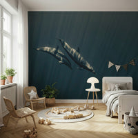 Deep Blue Journey wallpaper mural of two dolphins in sunlit blue water behind a white bed and wooden train rug in a child's bedroom