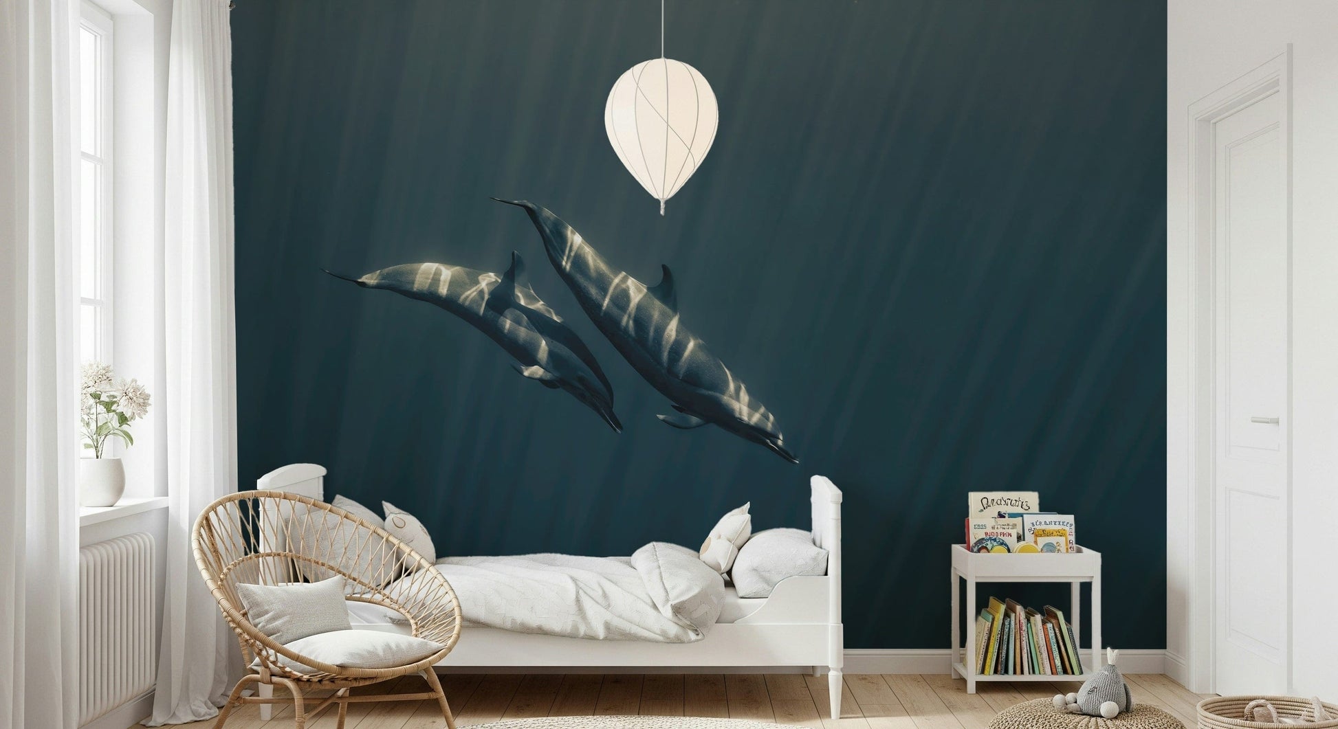 Deep Blue Journey wallpaper mural of two dolphins gliding through teal water above a white bed and rattan chair in a child's room