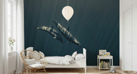 Deep Blue Journey wallpaper mural of two dolphins gliding through teal water above a white bed and rattan chair in a child's room