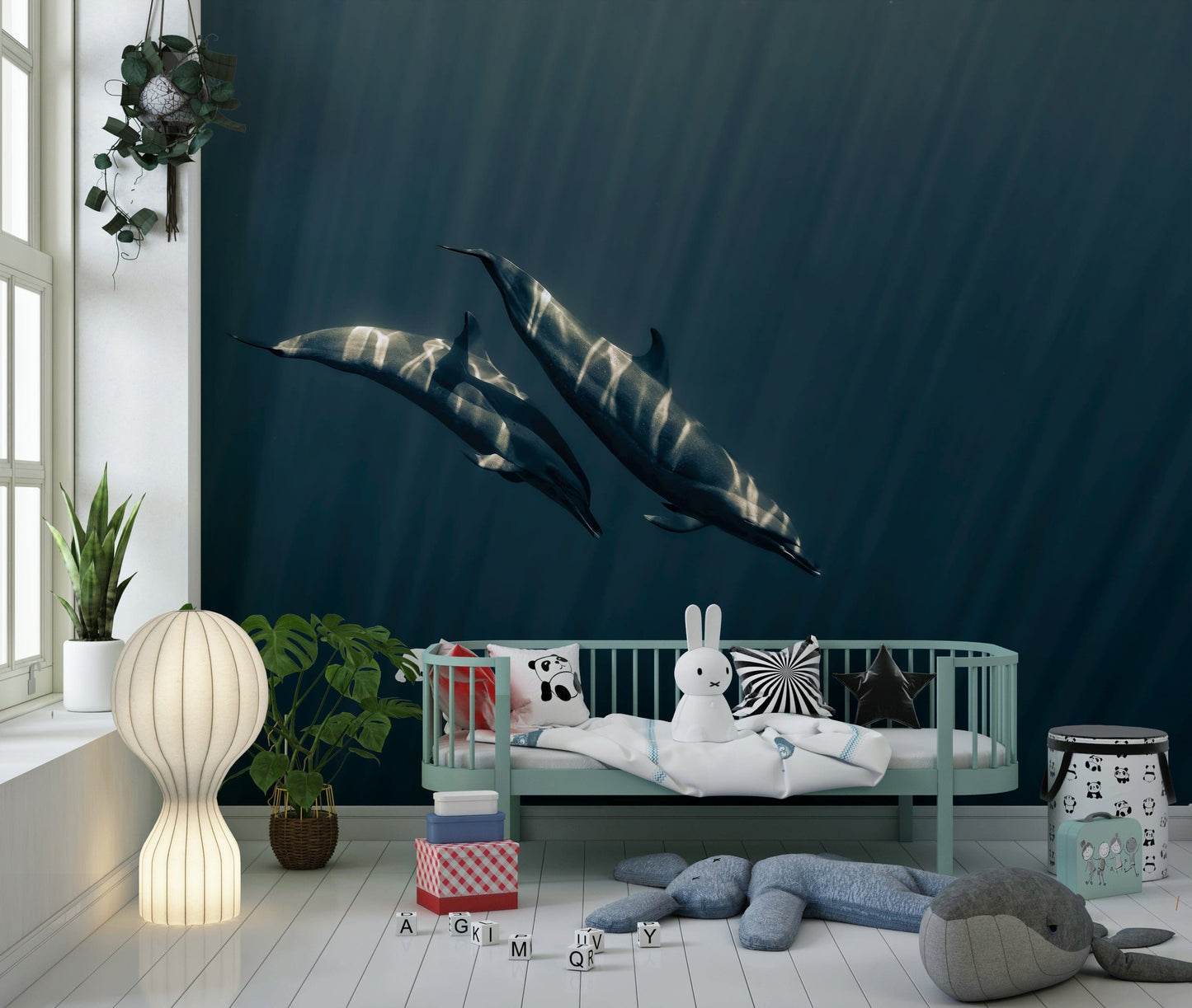 Deep Blue Journey wallpaper mural of two dolphins in deep blue ocean behind a mint daybed and whale plush in a kids room