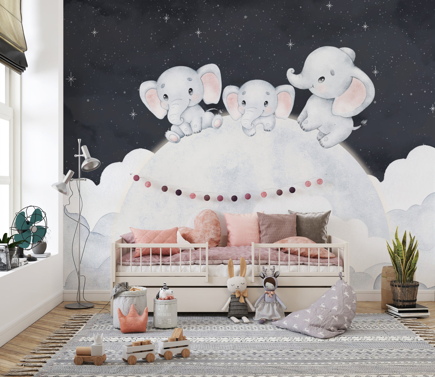 Dreamy baby elephant wallpaper mural with elephants on a moon above a child's bed with pink bedding in a nursery
