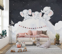 Dreamy baby elephant wallpaper mural with elephants on a moon above a child's bed with pink bedding in a nursery