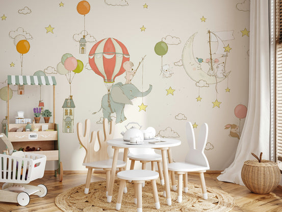 Moonlight Balloon Flight mural with elephant and hot-air balloon above a white bunny-ear table in a beige nursery