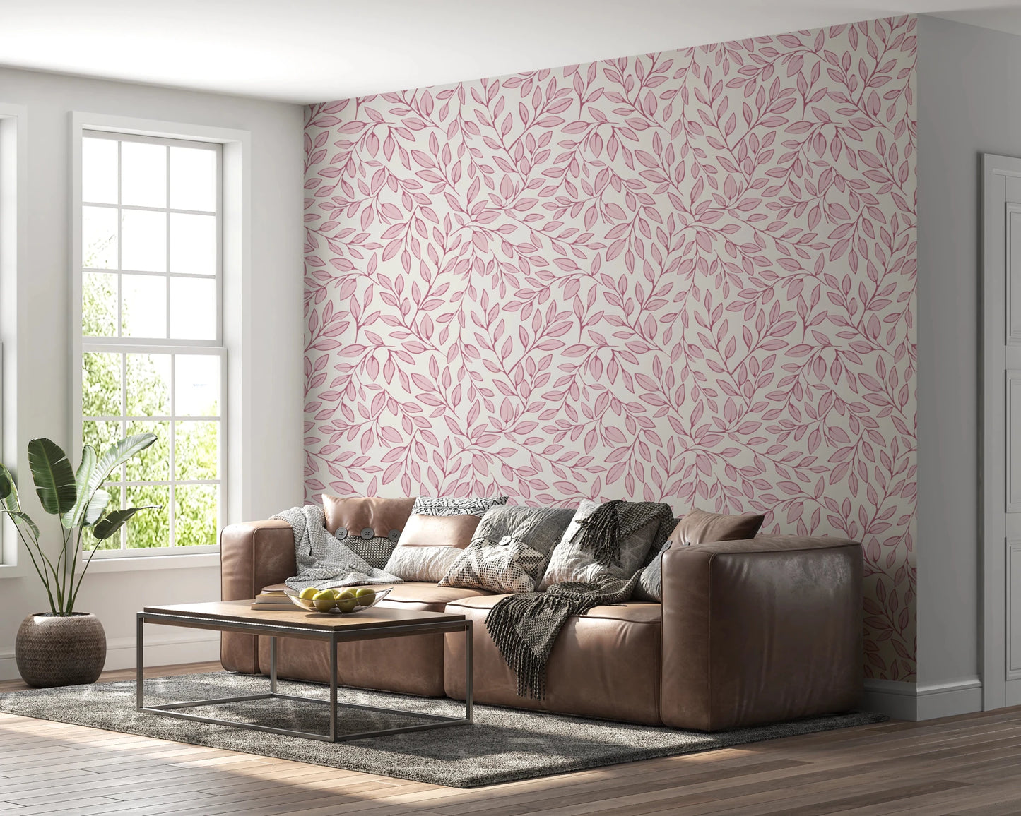 Dusty Rose Vines wallpaper of pink foliage on cream behind a brown leather sectional by a bright window