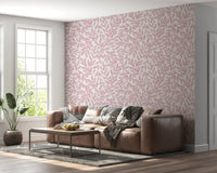 Dusty Rose Vines wallpaper of pink foliage on cream behind a brown leather sectional by a bright window