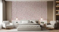 Dusty Rose Vines wallpaper of pink leaves on cream behind a grey upholstered bed flanked by armchairs