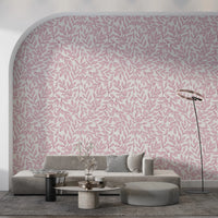 Dusty Rose Vines wallpaper with pink leaves on an arched wall behind a grey sofa and round travertine table