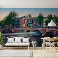 Dutch Canal Dreams wallpaper mural of Amsterdam canal houses behind a white bench and pale wood dining chairs