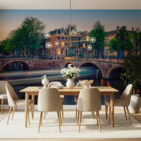 Dutch Canal Dreams wallpaper mural of an Amsterdam canal and arched bridge behind a wood dining table and beige chairs