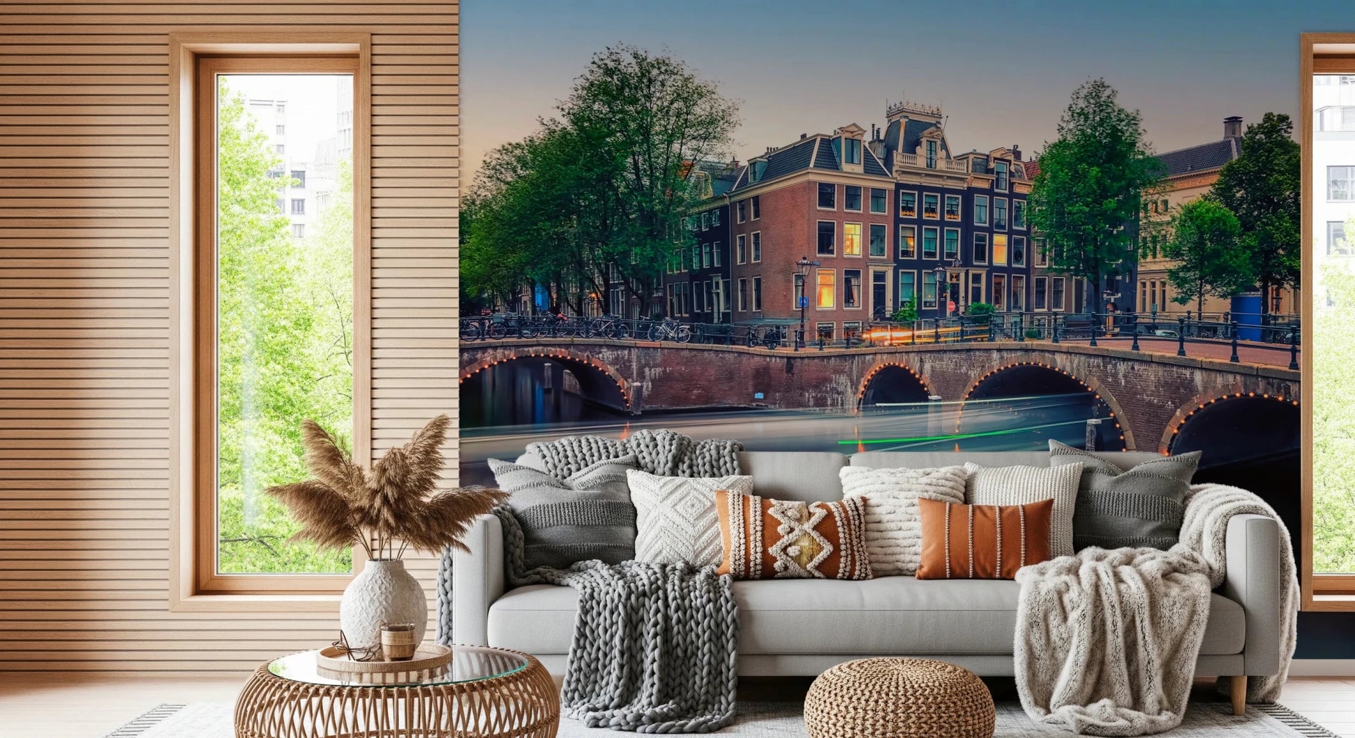 Dutch Canal Dreams wallpaper mural of dusk canal houses above a grey sofa piled with knit and tan throw pillows