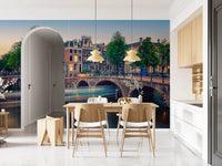 Dutch Canal Dreams wallpaper mural showing the lit canal bridge beside a pale wood dining set in a bright kitchen