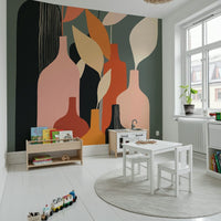 Earthy Hues Bottle Decor wallpaper mural in pink on dark green behind a white kids table in a playroom