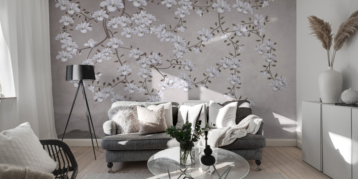 Floral Branches Mountain wallpaper mural of white magnolias on gray behind a tufted sofa and black tripod lamp