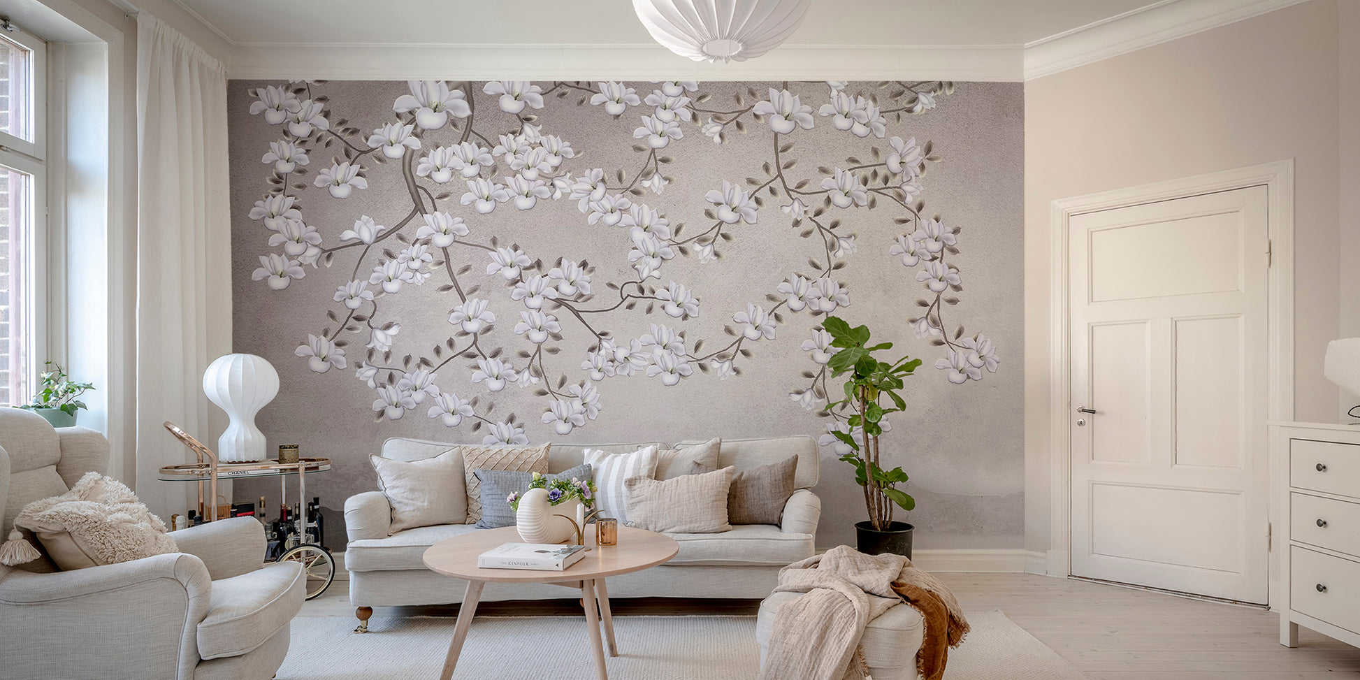 Floral Branches Mountain wallpaper mural with white magnolia branches behind a cream sofa in a bright living room