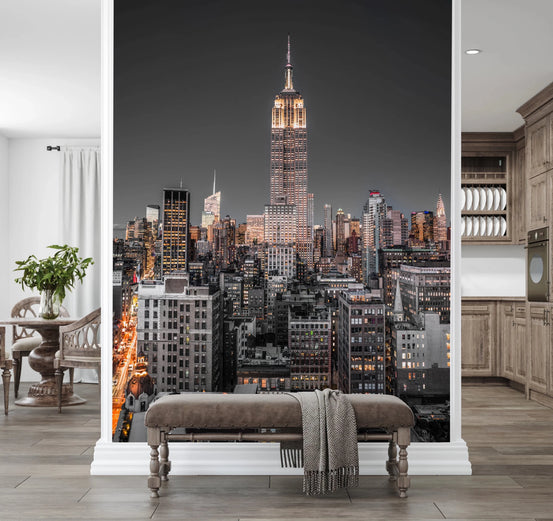 Empire State Building mural of the lit skyline above an upholstered bench in a wood-toned entryway