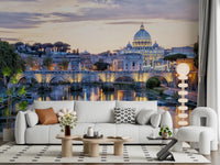 Eternal City Lights wallpaper mural of Rome at dusk above a white sofa with an orange pillow and bobble floor lamp