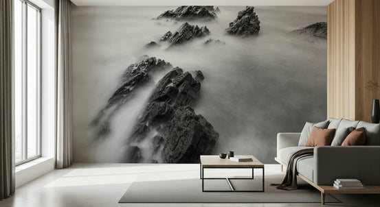 Ethereal Crags wallpaper mural of black and white misty rocks behind a grey sofa with rust pillows in a bright living room