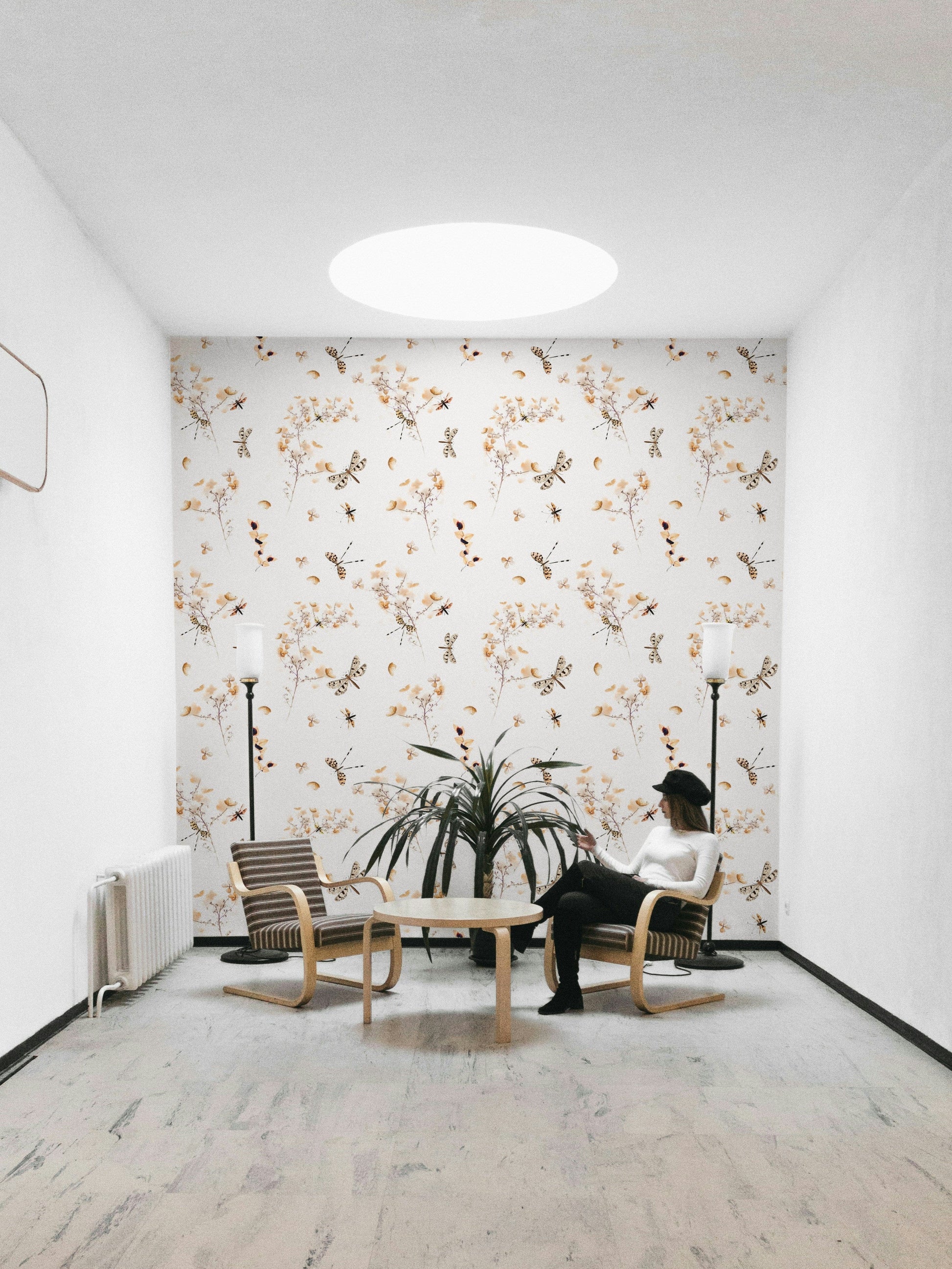 An angled shot of a wall with floral and insect wallpaper

