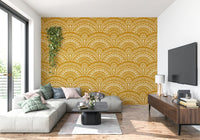 Ethnic Echoes wallpaper in mustard yellow behind a grey sectional sofa and TV in a bright living room