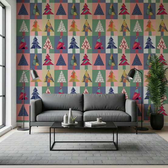 Festive Forest wallpaper of patchwork Christmas trees behind a grey sofa with black floor lamps and table