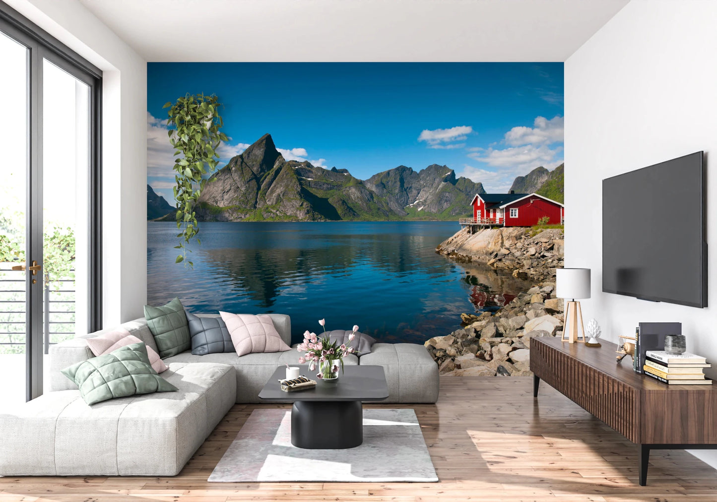 Fishing huts wallpaper mural of a blue fjord and red cabin behind a grey sectional sofa and wood TV console in a living room