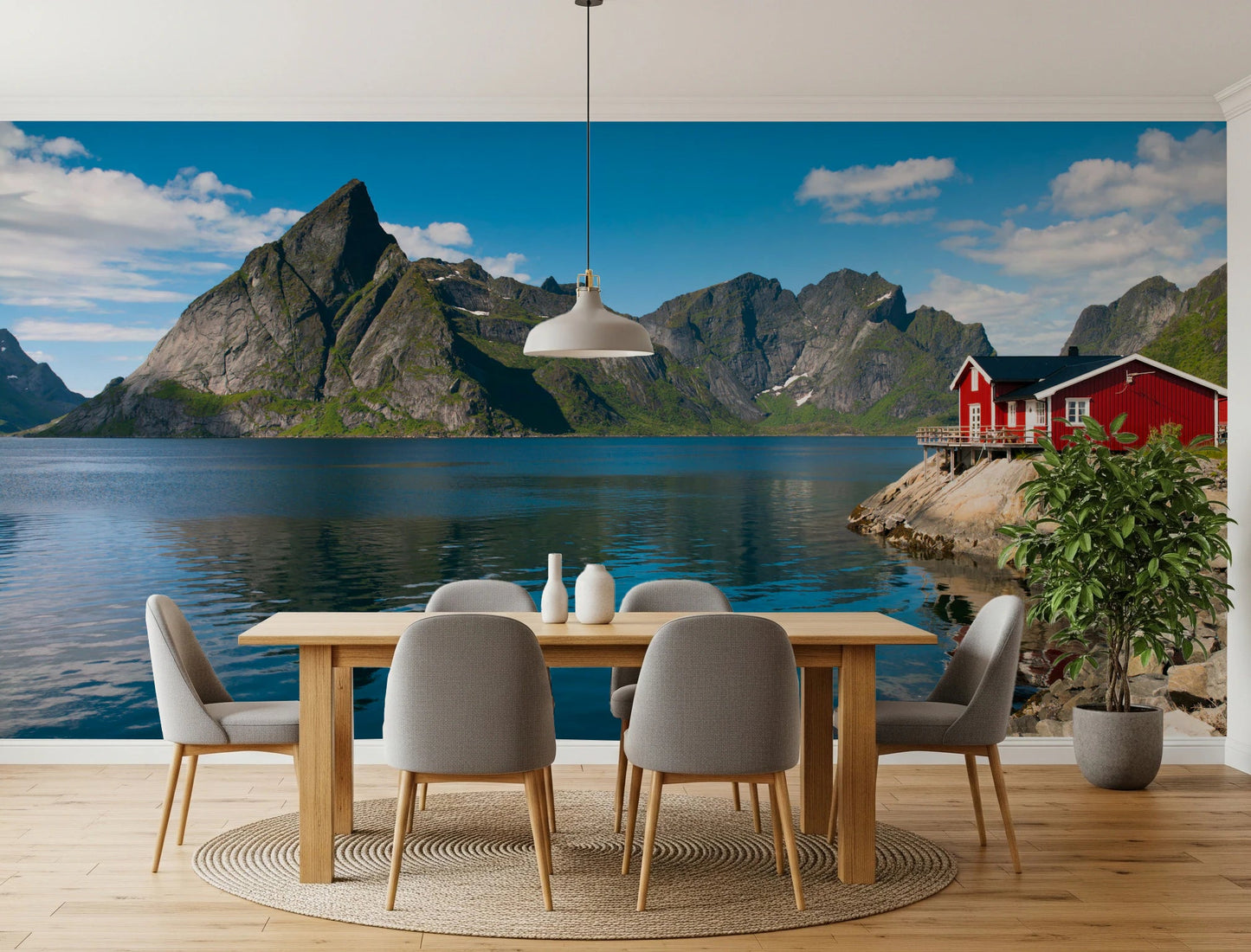 Fishing huts wallpaper mural of a Norwegian fjord and red cabins in a dining room with a light wood table and grey chairs