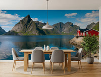 Fishing huts wallpaper mural of a Norwegian fjord and red cabins in a dining room with a light wood table and grey chairs