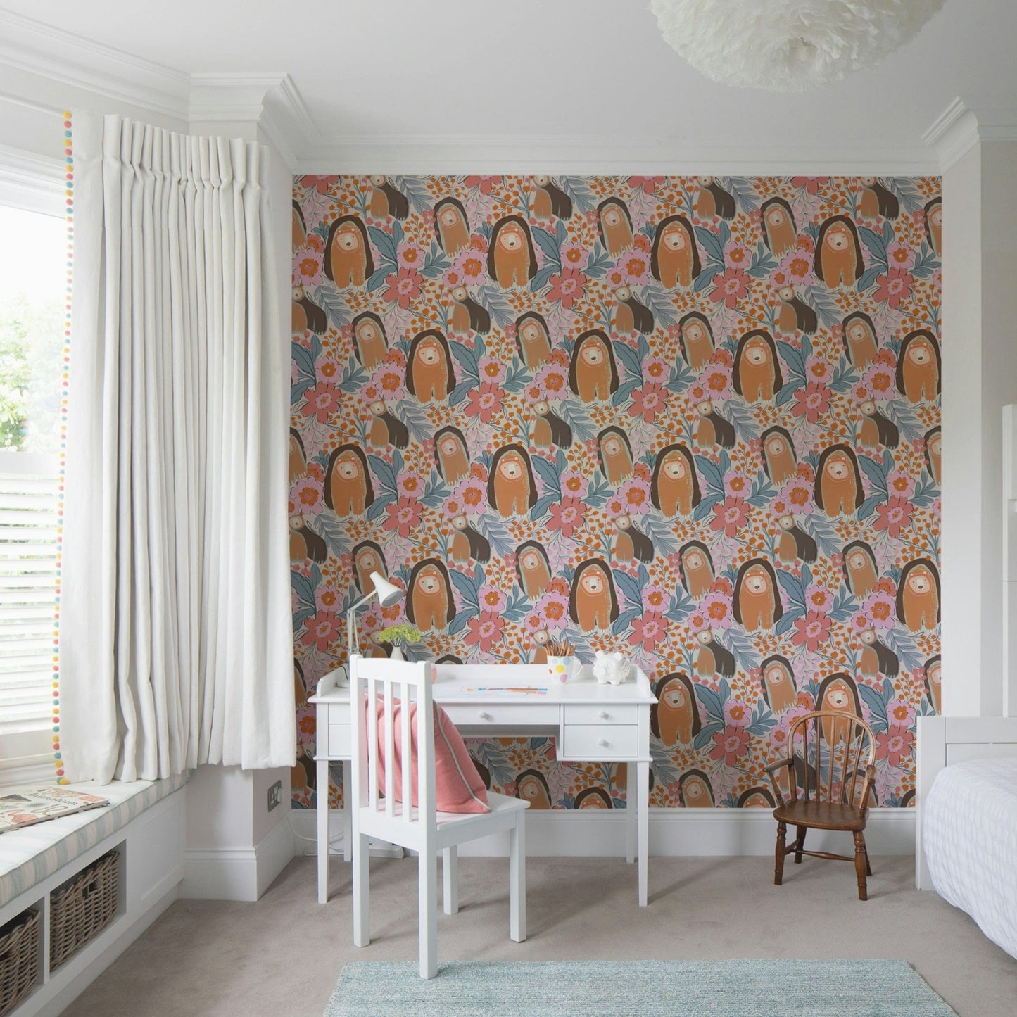 Floral bear wallpaper behind crib in nursery, calm beige and pink color tones