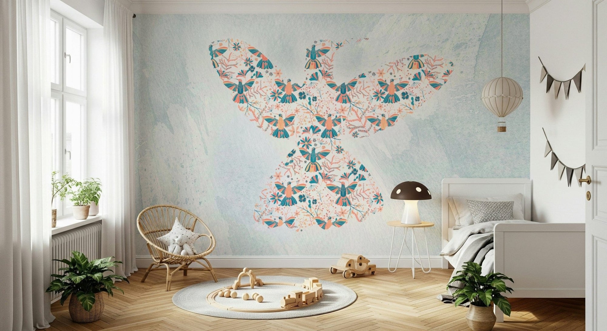 Floral Hummingbird wall mural in teal and coral on pale blue behind a rattan chair in a bright nursery