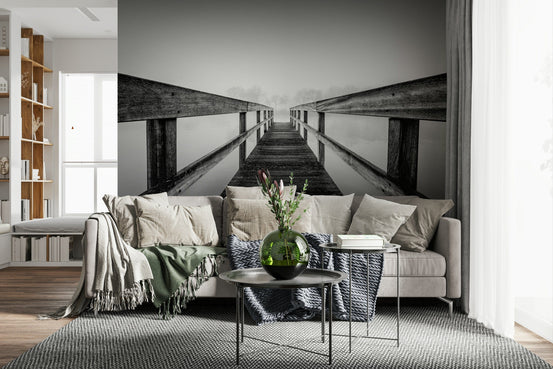 Foggy Bridge View wallpaper mural of a black-and-white misty wooden pier behind a beige sectional sofa in a living room